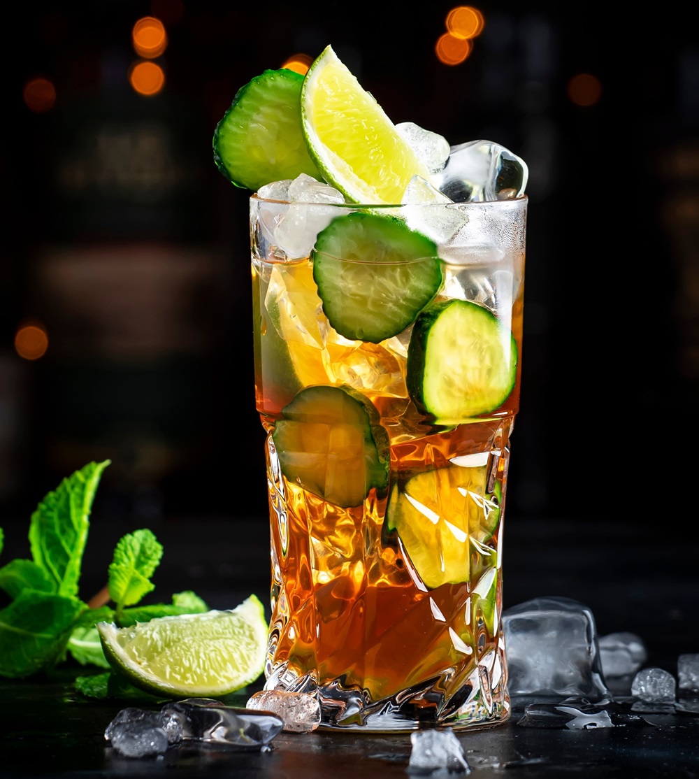 Glas mit Weißbierspritz und Eiswürfeln gefüllt, vor dunklem Hintergrund
