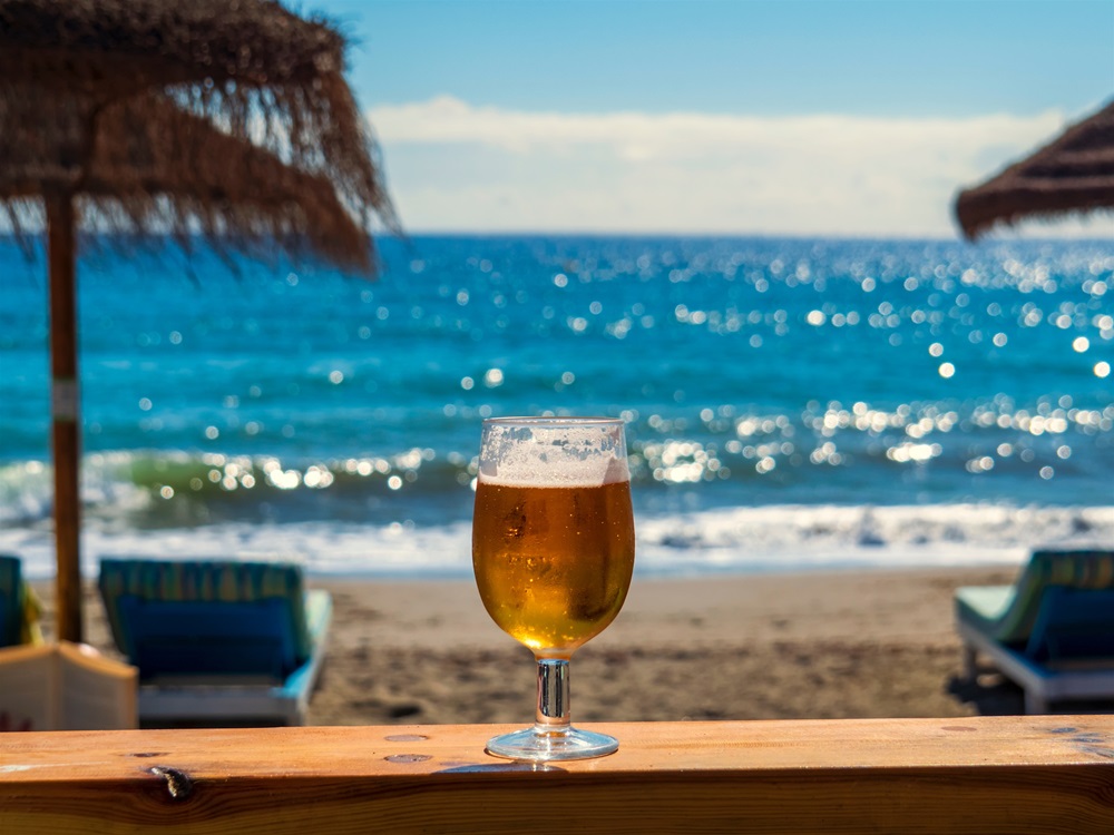 Bierglas auf Thresen stehend, im Hintergrund Strand und Meer